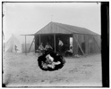  Wilbur with visitors and fellow campers in front of the Wrights' work shed at Kitty Hawk, North Carolina. Left to right: Edward C. Huffaker and Octave Chanute seated, Wilbur Wright standing, and George Spratt sitting on ground.

