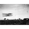 Wright pilot (possibly Brookins) flying a Wright transitional in front of grandstands.