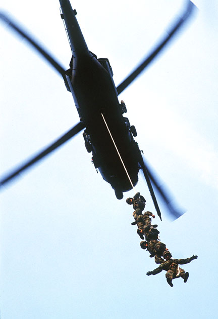 U.S. Army Special Forces personnel attached to Special Patrol Insertion-Extraction (SPIE) rigging are hoisted into the air by an MH-60G Pave Hawk helicopter. 